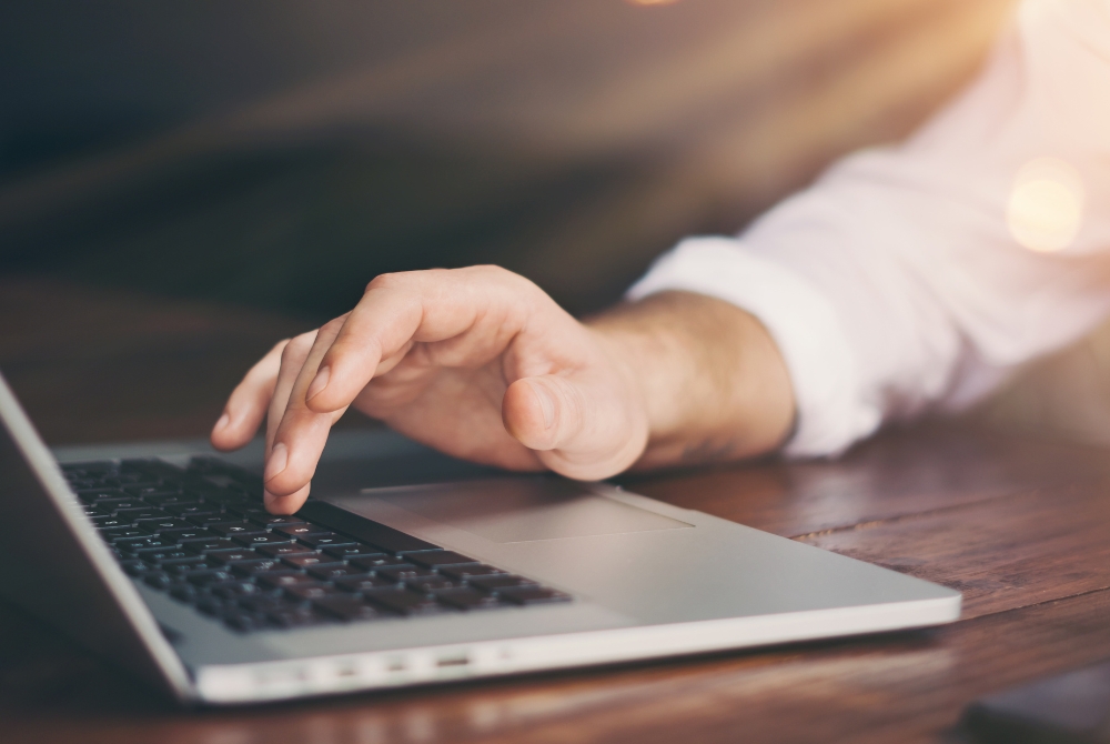 Close-up of hand using laptop: "Professional using laptop to manage real estate listings" — This can be added to a contact or about page where the focus is on personalized services and direct interaction with clients through modern technology.