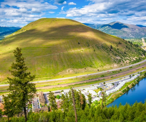 Scenic view of Alberton, Montana with a green hill, highway, and river