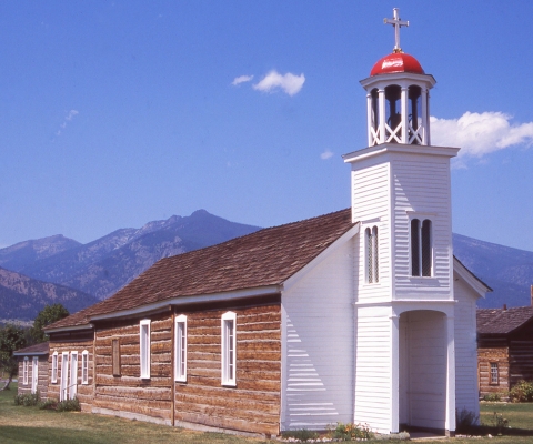 Historic wooden church with a red dome and mountain backdrop in Stevensville, Montana